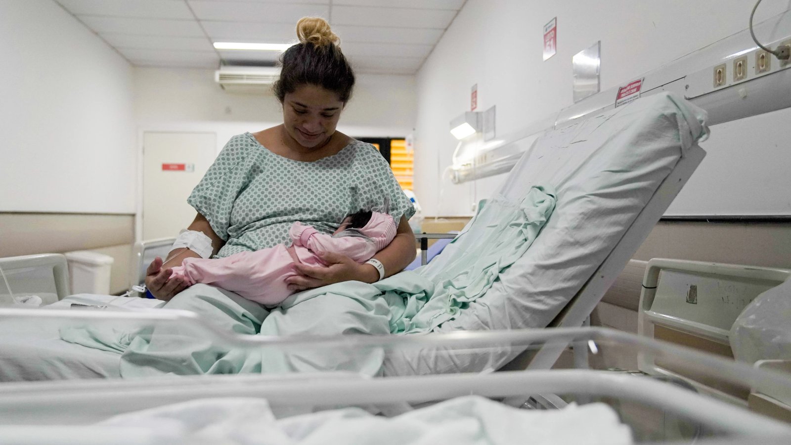 uma mulher com seu bebê num leito do hospital da mulher